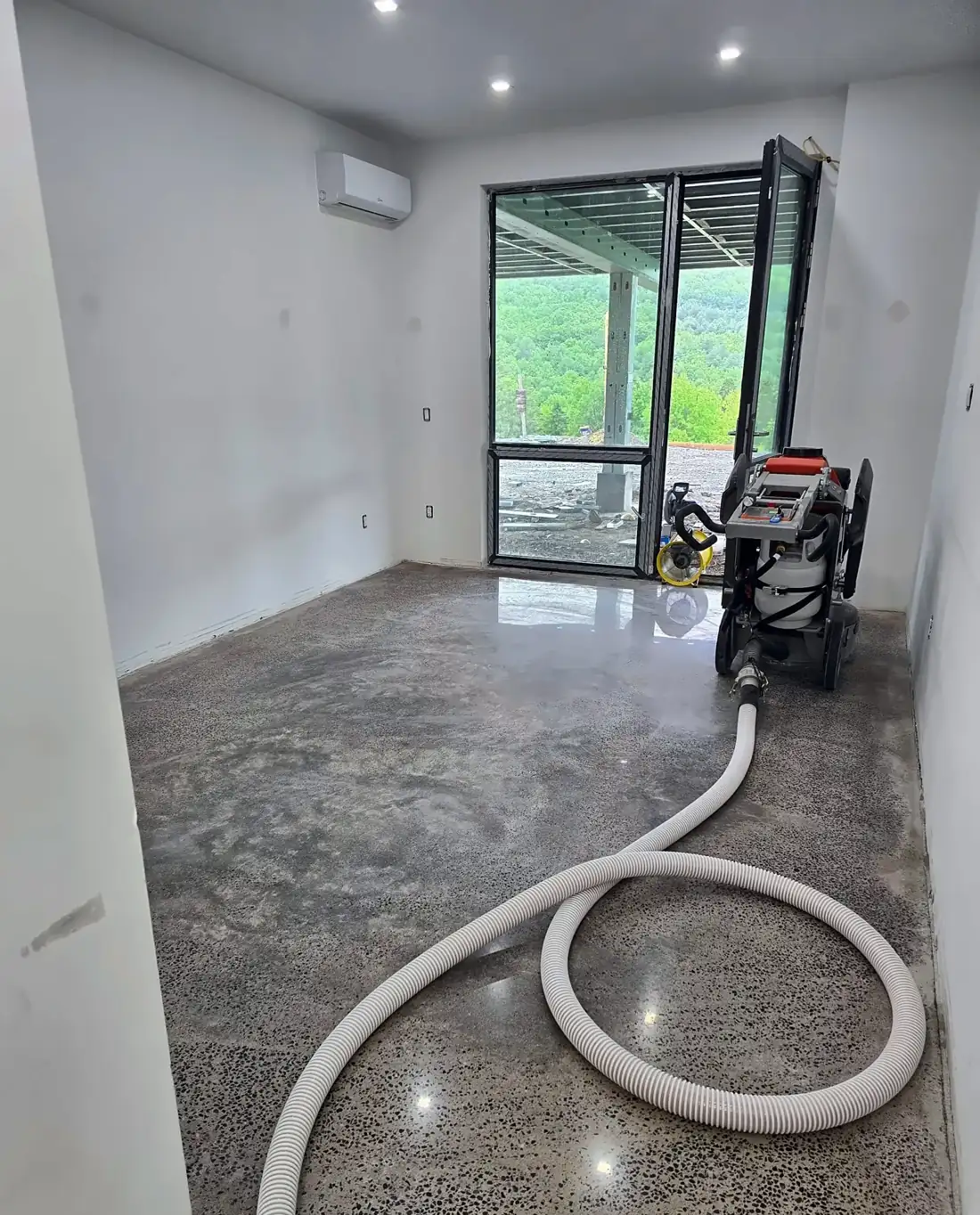 Concrete floor mid-grind with dust collection hose